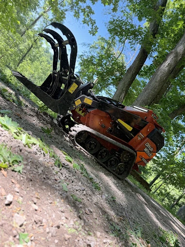Grapple loader lifting a load of cut brush toward the chipper on a residential property near Pittsburgh, PA